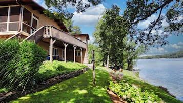Un chalet au bord du lac, doté d’une terrasse en bois, d’un porche abrité et offrant une vue sur le lac.