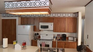 Una cocina con armarios de madera, un refrigerador blanco, un microondas, una estufa y una cafetera.