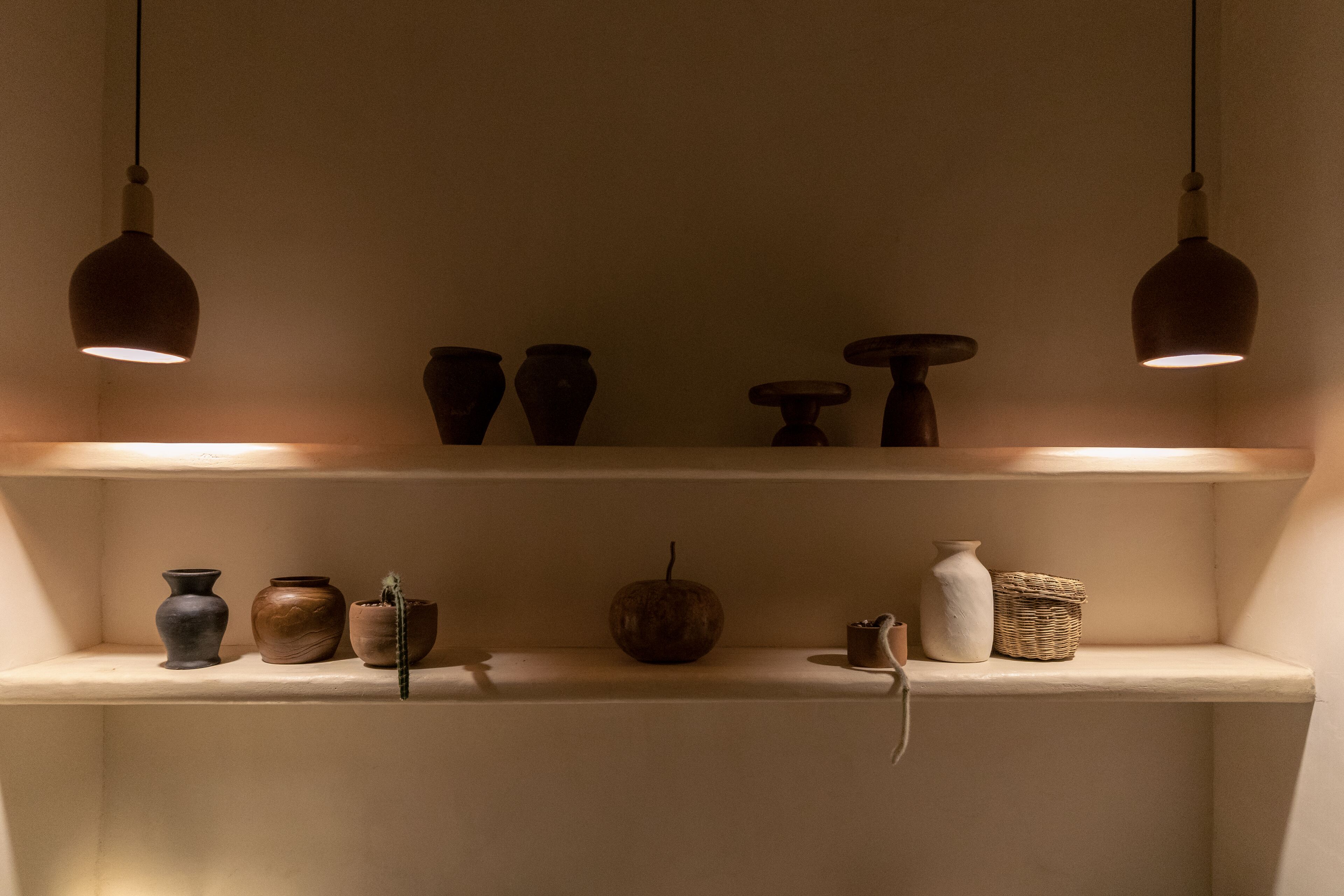 A shelf with various pottery items and a hanging light fixture.