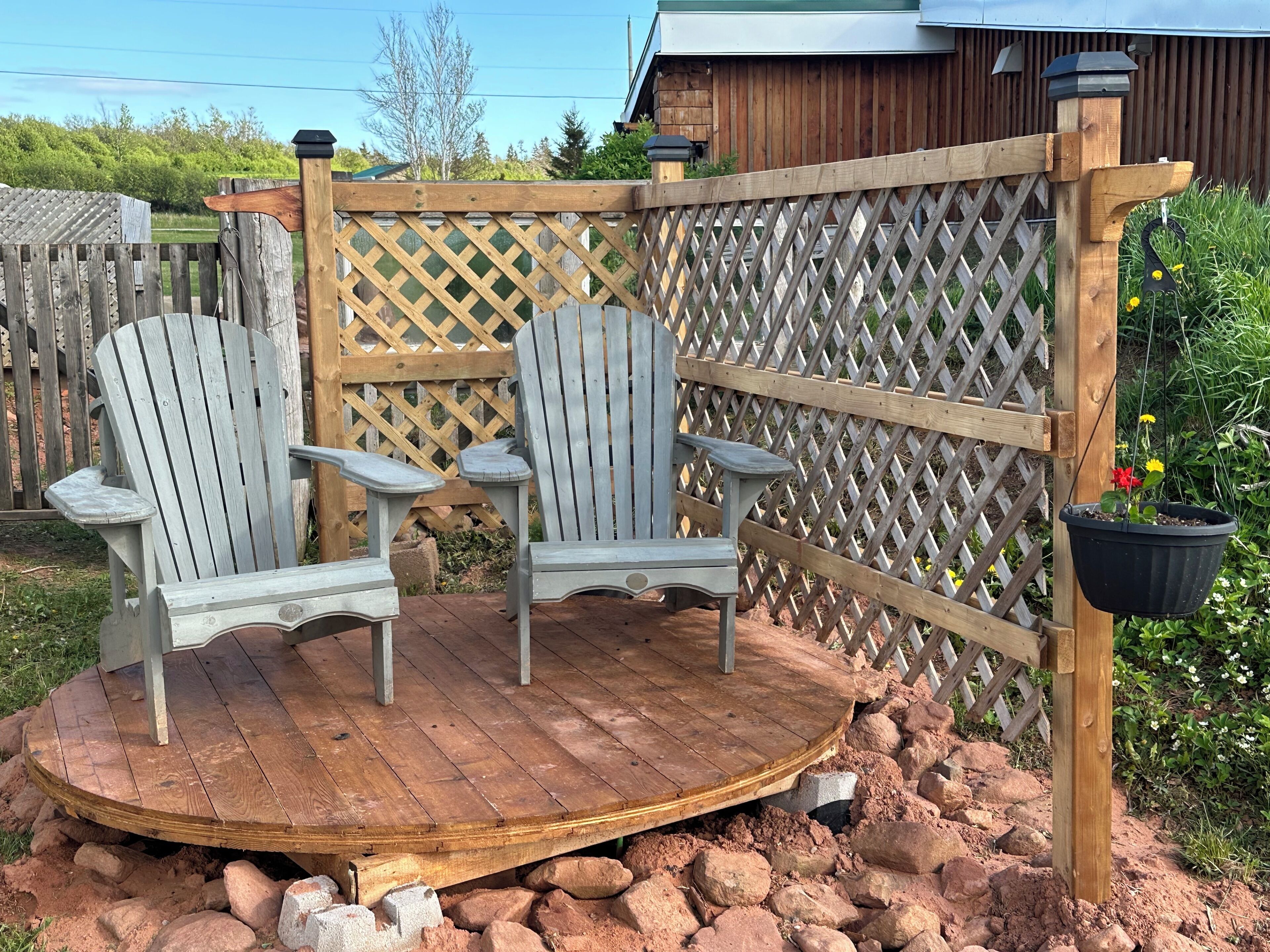 A wooden deck with Adirondack chairs and a lattice fence.