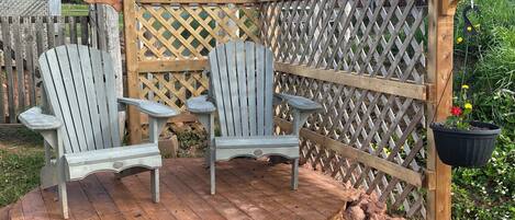 A wooden deck with Adirondack chairs and a lattice fence.
