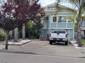 A residential driveway with a white pickup truck parked in front of a two-story house with blue siding and a front porch. - Victoria home near to downtown  oakland!!! (Oakland)