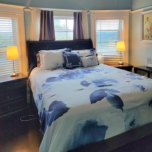 A bedroom with a large bed, two bedside tables, a headboard, and a window with curtains. - Victoria home near to downtown  oakland!!! (Oakland)