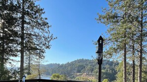 A wooden deck with a telescope, benches, and a railing overlooking a lake and forested hills. - Dogs are family also 240° Lakefront View Spacious modern Family Retreat sleeps 8 (Crestline)