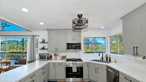 A modern kitchen with grey cabinets, stainless steel appliances, and a large island. - Dogs are family also 240° Lakefront View Spacious modern Family Retreat sleeps 8 (Crestline)