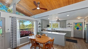 A modern kitchen with a central island, grey cabinets, and a dining area with a wooden table and chairs. - Dogs are family also 240° Lakefront View Spacious modern Family Retreat sleeps 8 (Crestline)