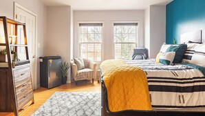 Une chambre avec deux lits, une commode, une chaise et une petite table.