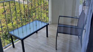 A balcony with a glass table and chairs, offering a view of a cityscape and greenery. - Luxury apartments  (La Romana)