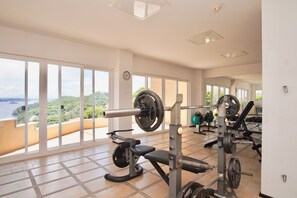 Een sportschool met grote ramen en uitzicht op een mooi landschap, voorzien van diverse fitnessapparaten.