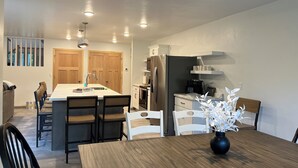 A modern kitchen with a central island, wooden cabinets, and a coffee maker. - Peaceful newly built home between Fish Creek and Ephraim, WI. 3 bed/ 2 bath. (Fish Creek)