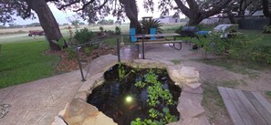Un bassin bordé de pierres, entouré d’une terrasse en bois et d’une rambarde en métal.