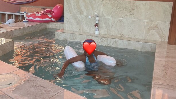Een hottub met een muurschildering van een dolfijn, een hangmat en een rode en witte opblaasbare poolfloat.