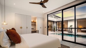 A modern bedroom with a large bed, a ceiling fan, and a view of an outdoor swimming pool. - Apricot House by Alfred in Bali (Pecatu)