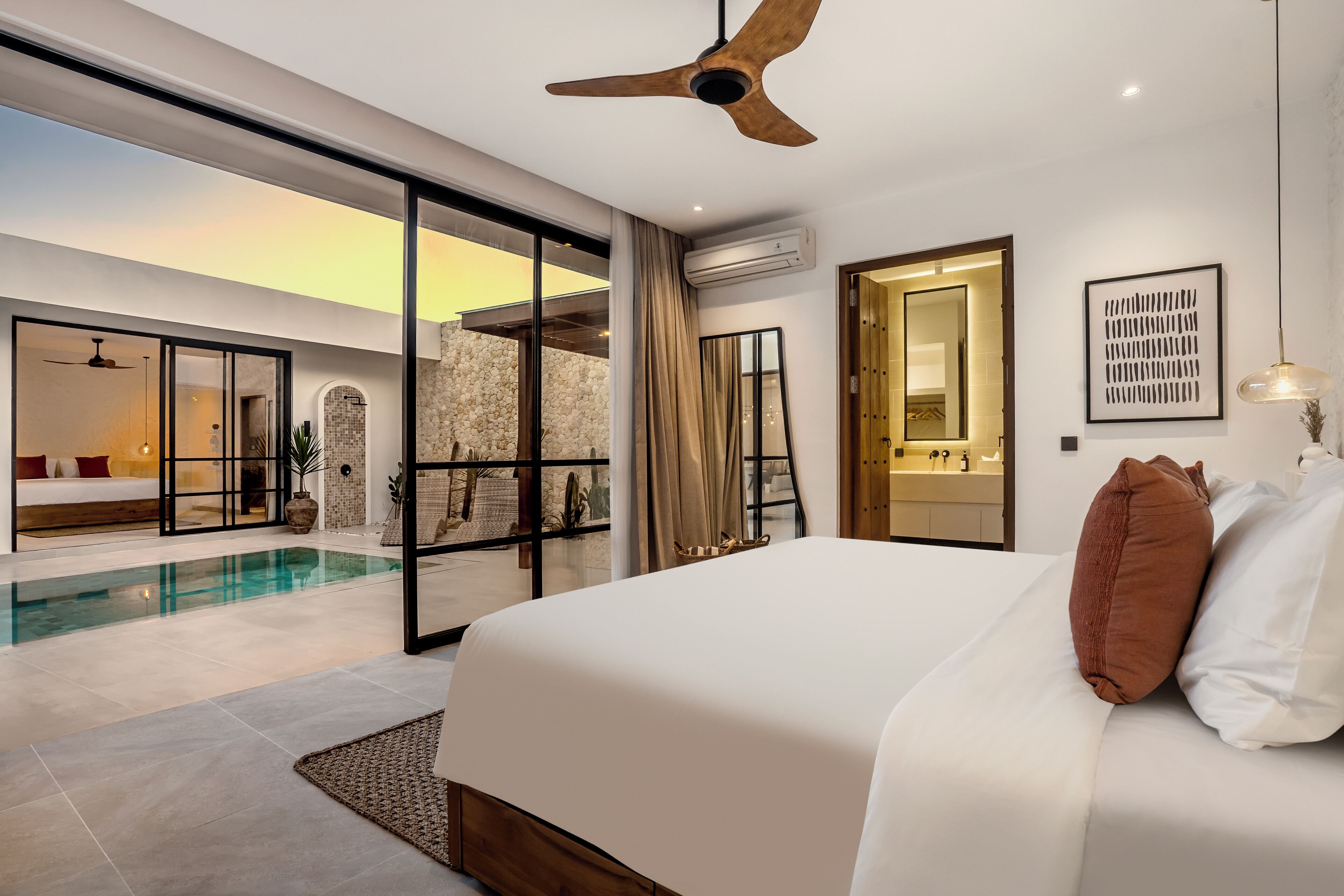 A modern bedroom with a large bed, a ceiling fan, and a view of a swimming pool.