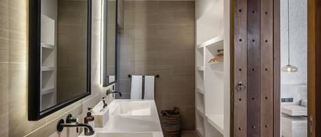 A modern bathroom with a large mirror, two sinks, and a wooden door.