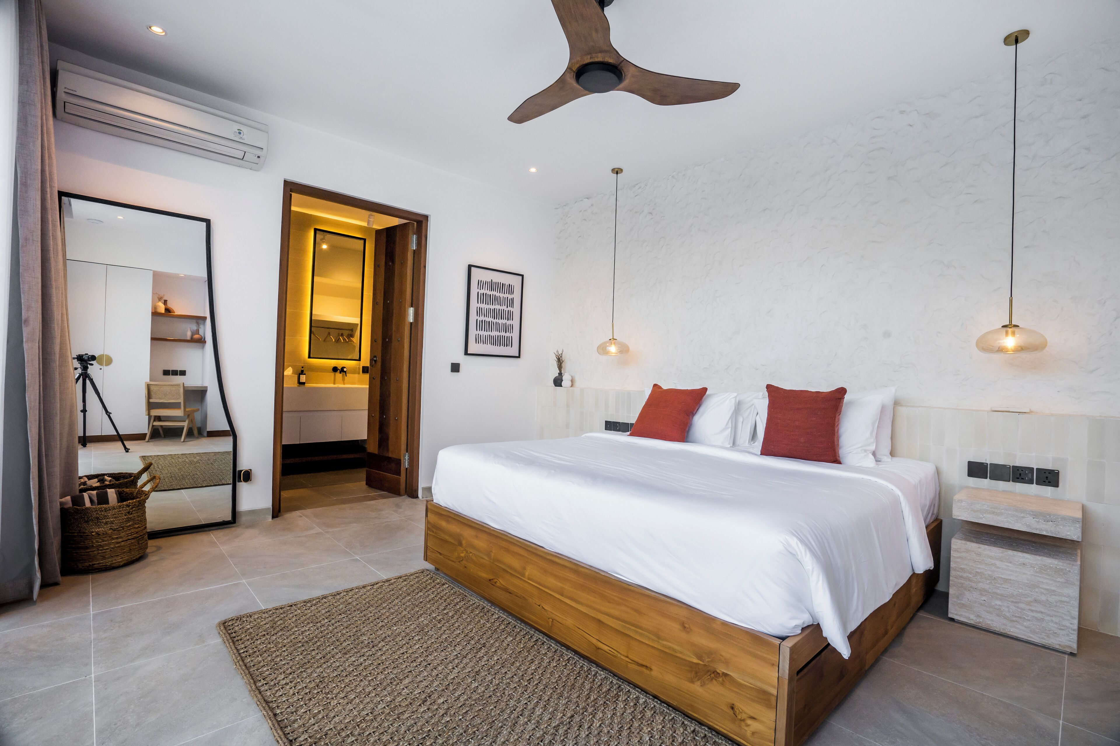 Un dormitorio moderno con cama de madera, ventilador de techo e iluminación colgante.