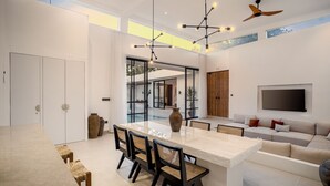 A spacious living area with a large central island, a sofa, and a TV mounted on the wall. - Apricot House by Alfred in Bali (Pecatu)