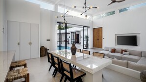 A spacious living area with a large island, seating, and a TV. - Apricot House by Alfred in Bali (Pecatu)