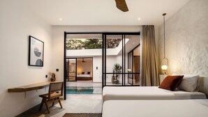 A modern hotel room with a large bed, a desk, and a view of the outdoor area. - Apricot House by Alfred in Bali (Pecatu)