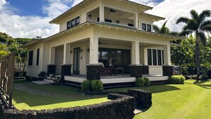 A two-story house with a covered porch, stone pillars, and a well-maintained lawn. - Admired Poipu beach house in a perfect location, now a vacation home! (Koloa)