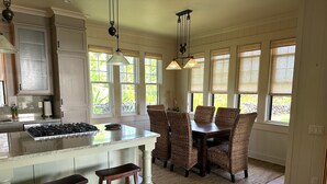 A kitchen with a central island, wooden chairs, and a dining table. - Admired Poipu beach house in a perfect location, now a vacation home! (Koloa)