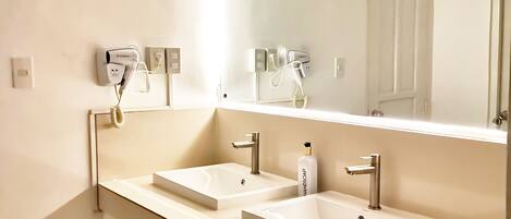 Une salle de bain moderne avec deux lavabos, un miroir et une poubelle.