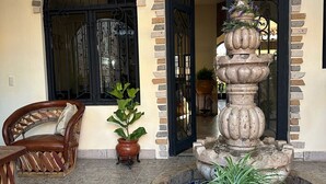 Un pati amb una font, una cadira de fusta i plantes en testos.