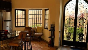 Una cuina amb barra, grans finestres i una reixa de ferro decorativa.