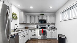 A modern kitchen with white cabinetry, stainless steel appliances, a microwave, oven, and a dishwasher. - Large Home in Quiet Neighborhood (Taylorsville)