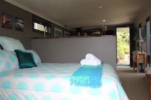 Relax in this serene bedroom with a large bed, a nightstand, and a window offering a view of lush greenery.