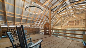 Un'ampia stanza mansardata con soffitto alto, travi in legno e un grande lampadario.
