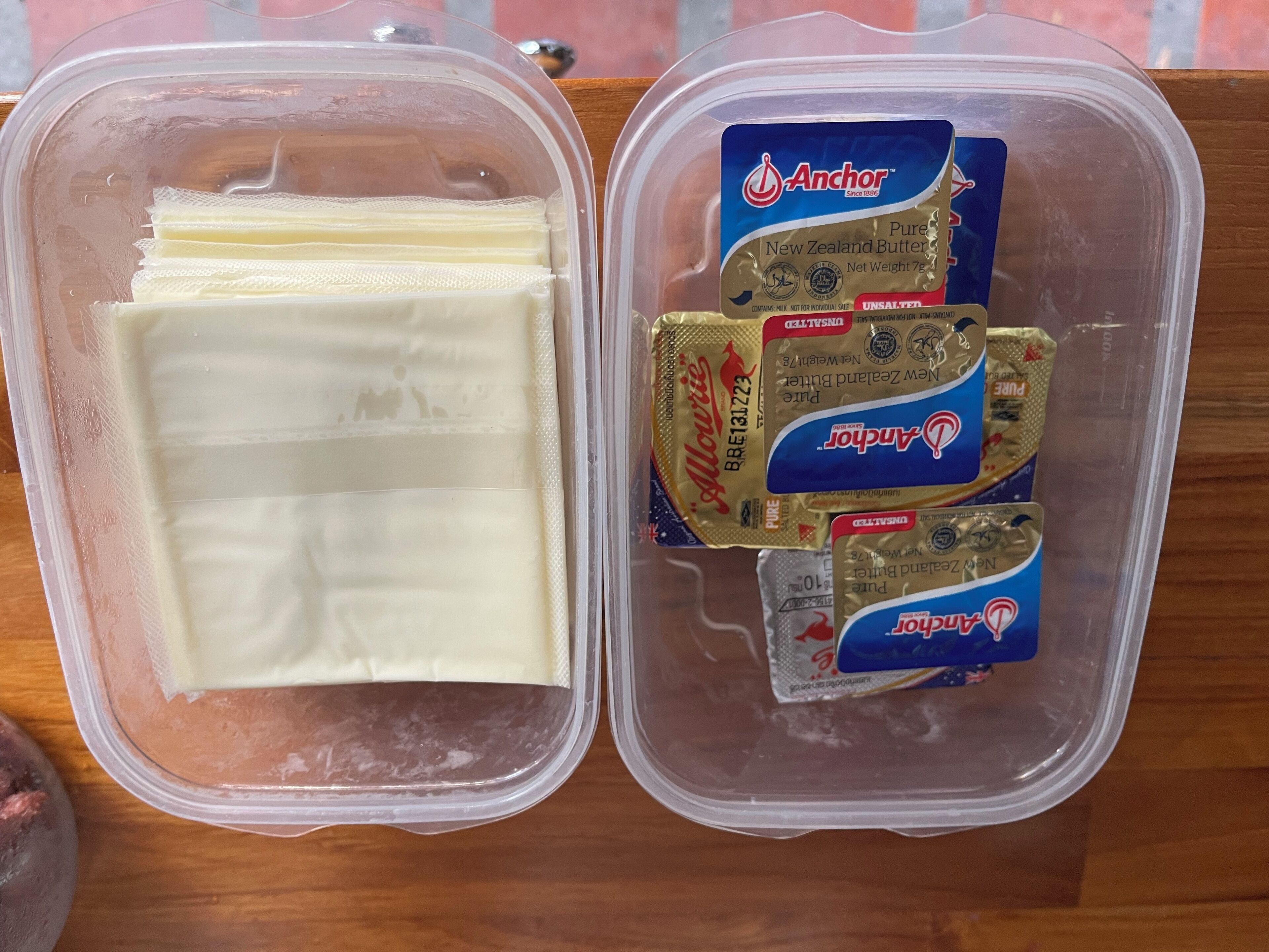 Two plastic containers, one with a white block and the other with two packages of Anchor butter.