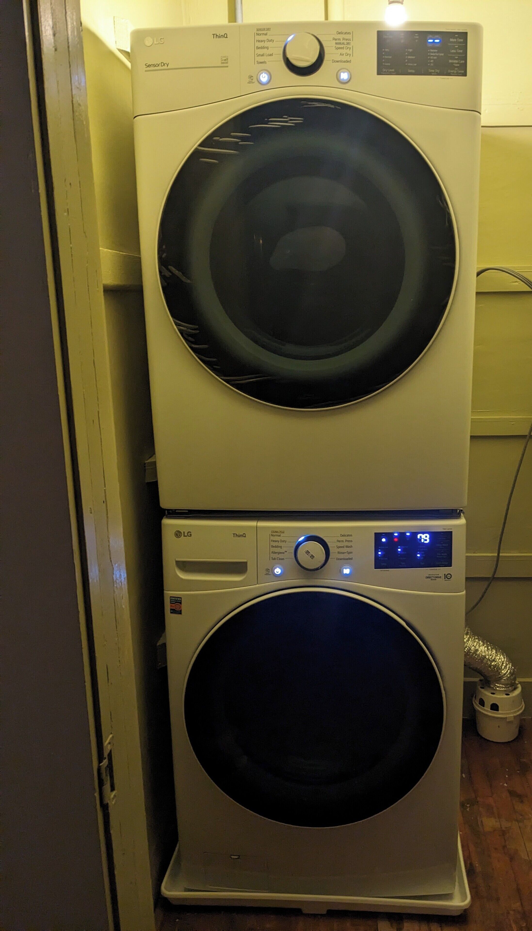 Two stacked LG ThinQ front-loading washing machines in a laundry room.