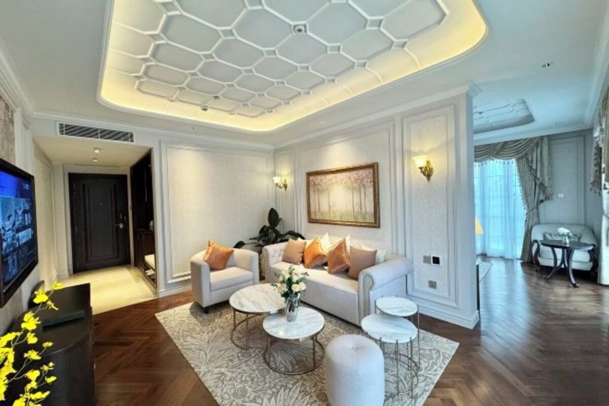 A modern living room with a white sofa, two round coffee tables, and a large painting on the wall.