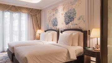 A double bed with white linens, a wooden headboard, and a floral wallpaper mural.