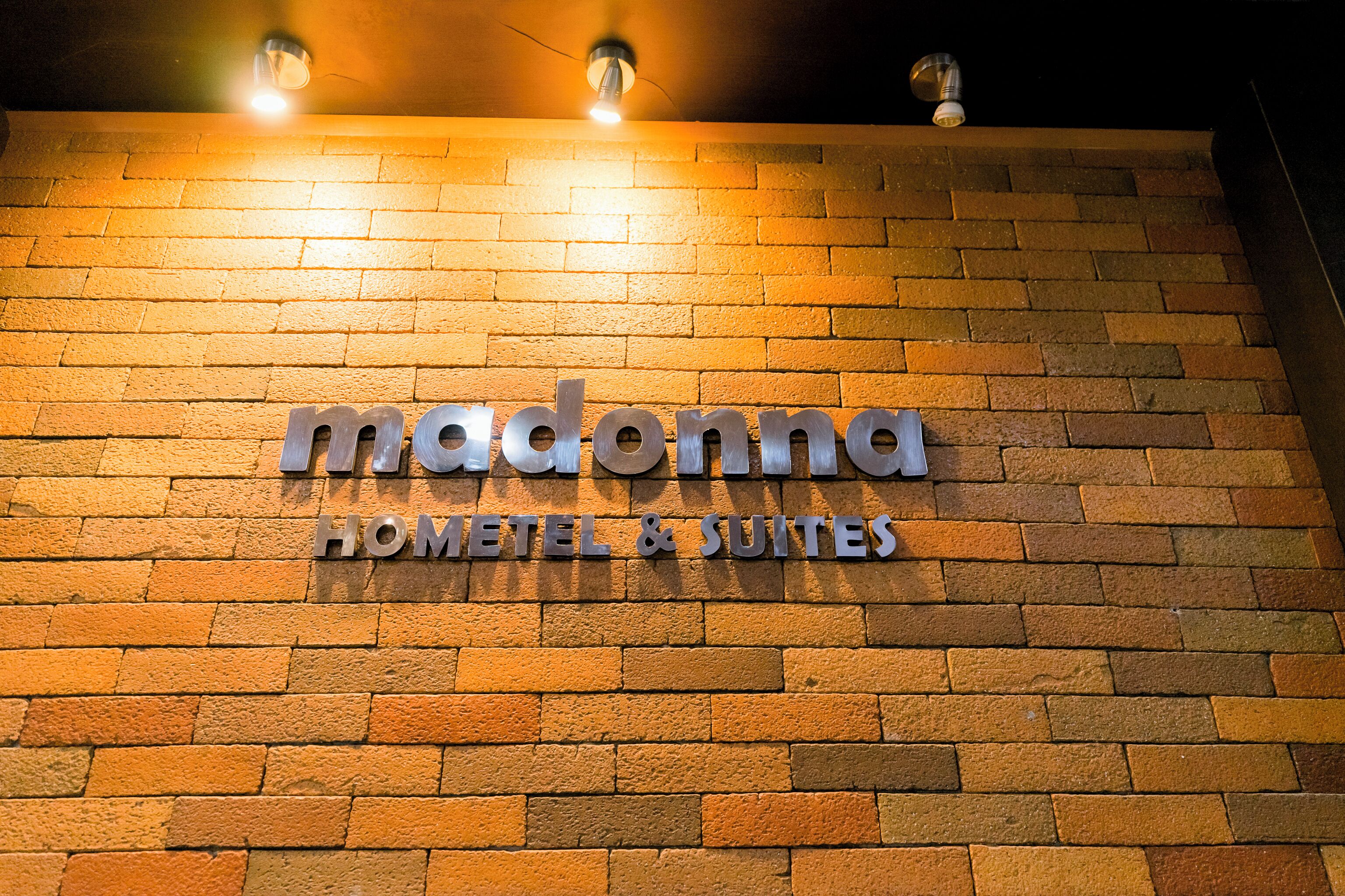 A brick wall with a sign that reads "Madonna Hotel & Suites."
