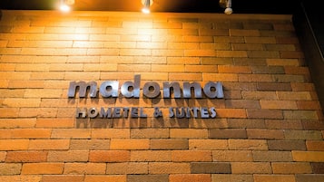 A brick wall with a sign that reads "Madonna Hotel & Suites."