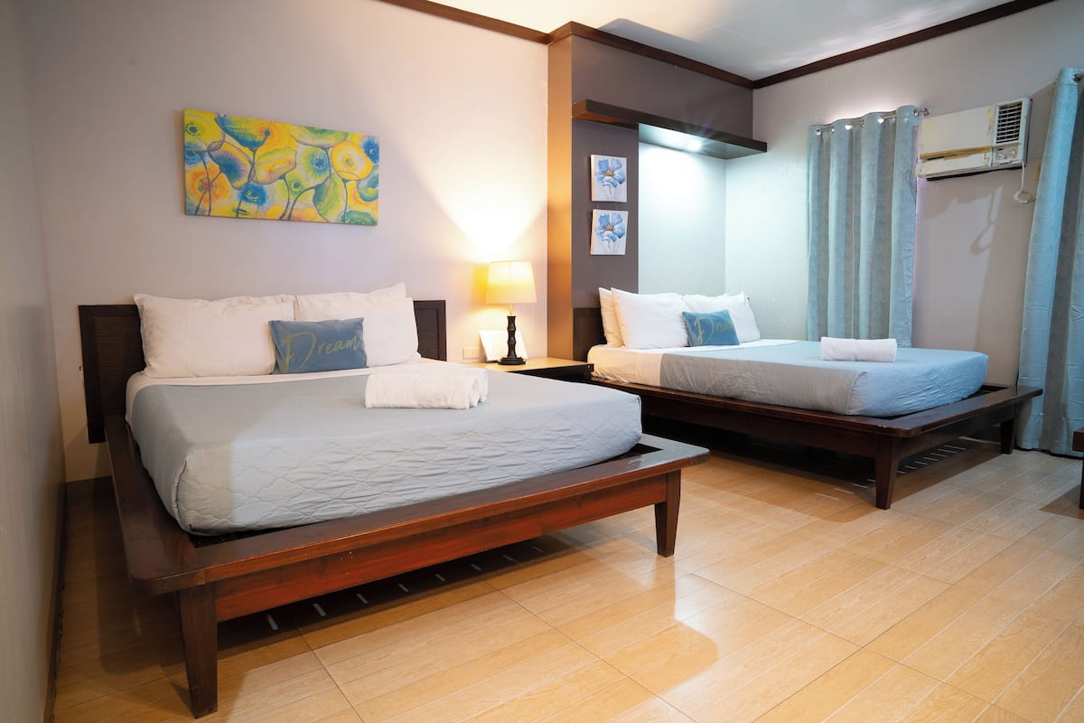 A hotel room with two beds, a ceiling fan, and a window with curtains.