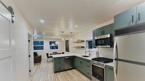 A modern kitchen with green cabinets, a stainless steel refrigerator, and a built-in oven. - Outlaw Inn Unit 4.  Newly Remodeled large unit! 2 minutes walk to Main Street.  (Ouray)