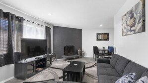 Ein modernes Wohnzimmer mit Flachbildfernseher, dunkelgrauem Sofa und Kamin.
