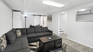 Ein modernes Wohnzimmer mit einer Eckcouch, einem Couchtisch und einer Treppe, die zu einer anderen Ebene führt.