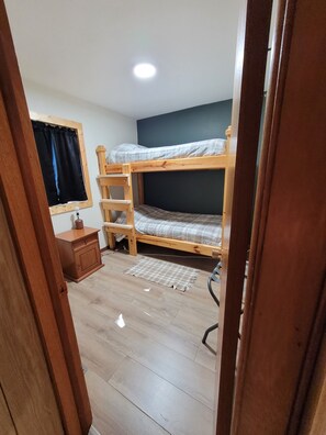 A room with a bunk bed, a small wooden cabinet, a desk, and a chair. - Main Street Home-Locally Owned-No Cleaning Fees-Pets Allowed (Webster)