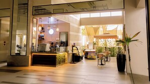 Un hall d’hôtel moderne avec un comptoir d’accueil, un espace salon et de grandes fenêtres.
