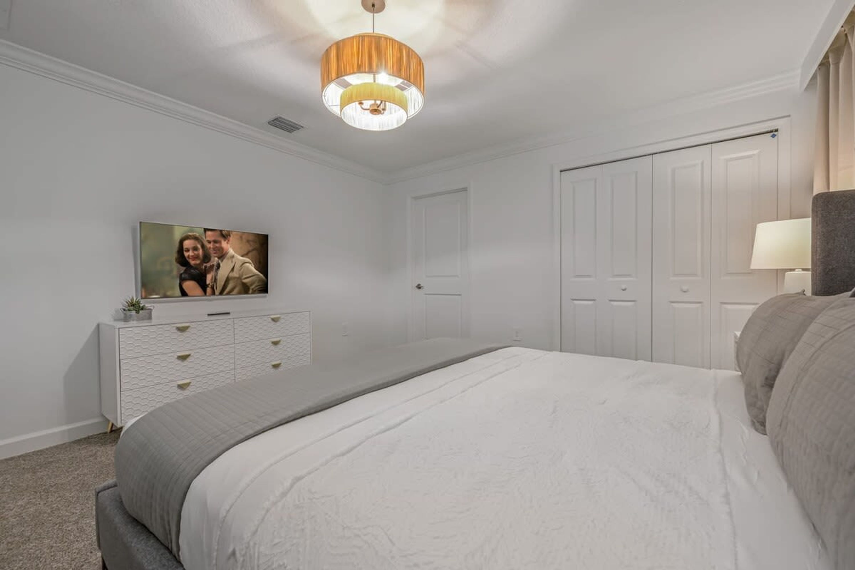 A bedroom with a bed, a dresser, a television, and a wardrobe.