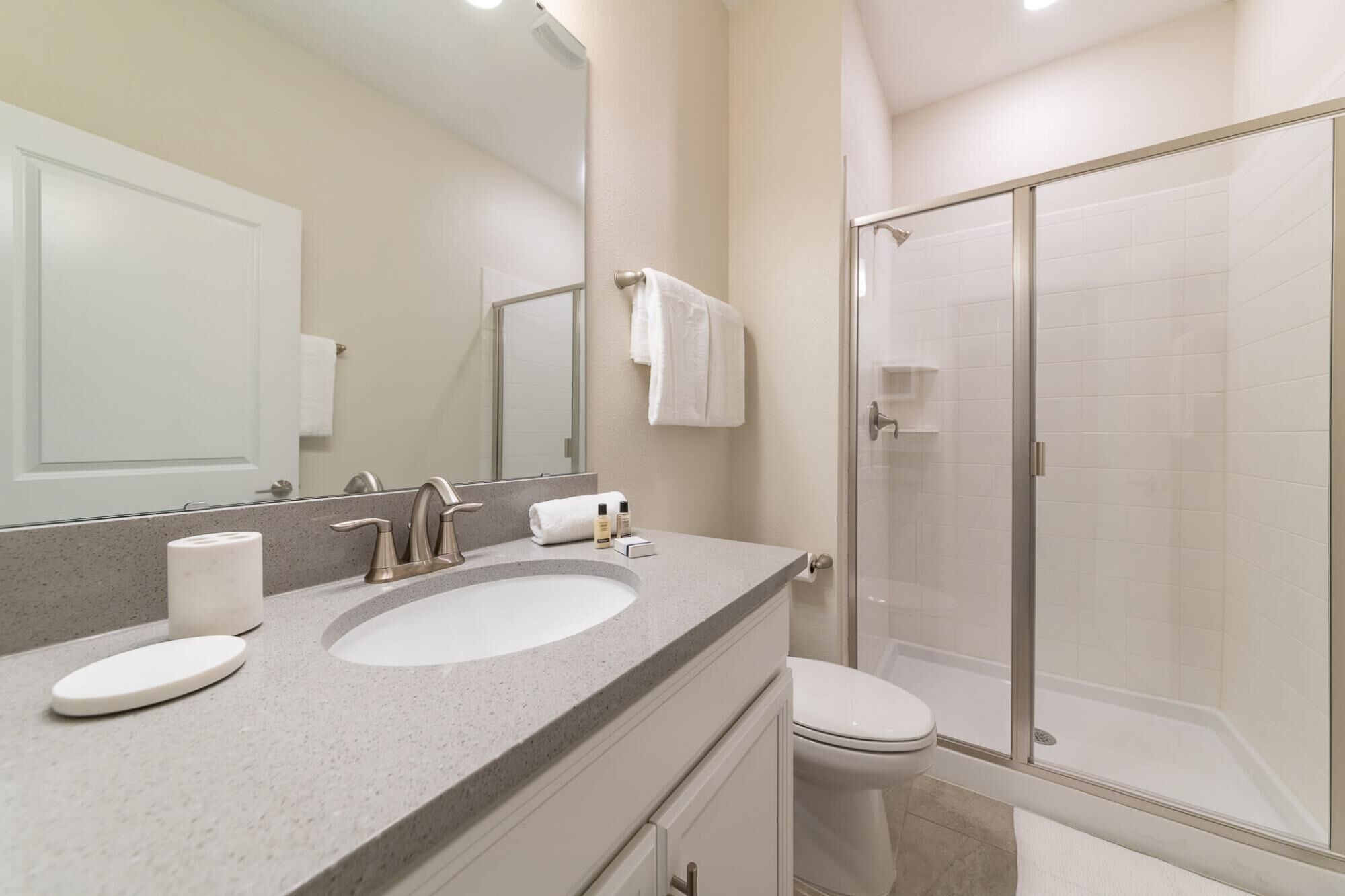 A modern bathroom with a double sink, a glass shower enclosure, and a toilet.
