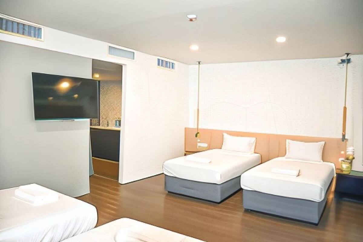 A hotel room with two beds, a TV, and a wooden floor.