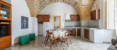 A kitchen with a stone ceiling, a dining area with a table and chairs, and a sofa.