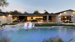Une maison moderne dotée d’une piscine, d’un espace salon extérieur et d’un patio bien éclairé.