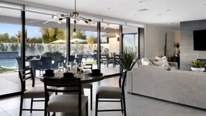 Une cuisine moderne dotée d’un grand îlot central, un coin repas avec une table et des chaises, et un espace de détente avec un canapé et une télévision.
