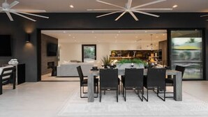 Un espace repas moderne avec une table centrale, des chaises et un ventilateur de plafond.